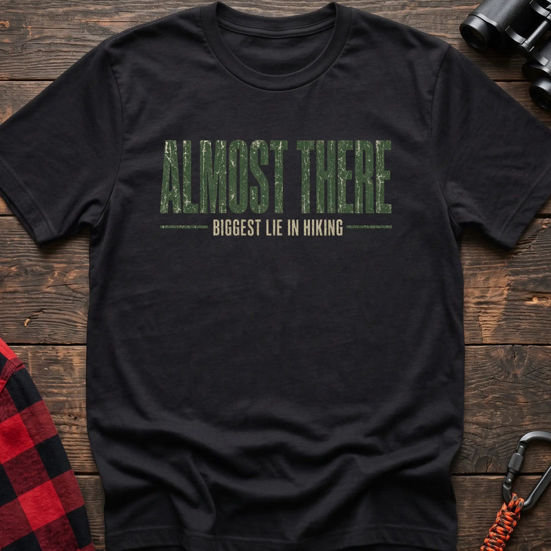 Black cotton t-shirt with Almost There Biggest Lie in Hiking text on rustic wood