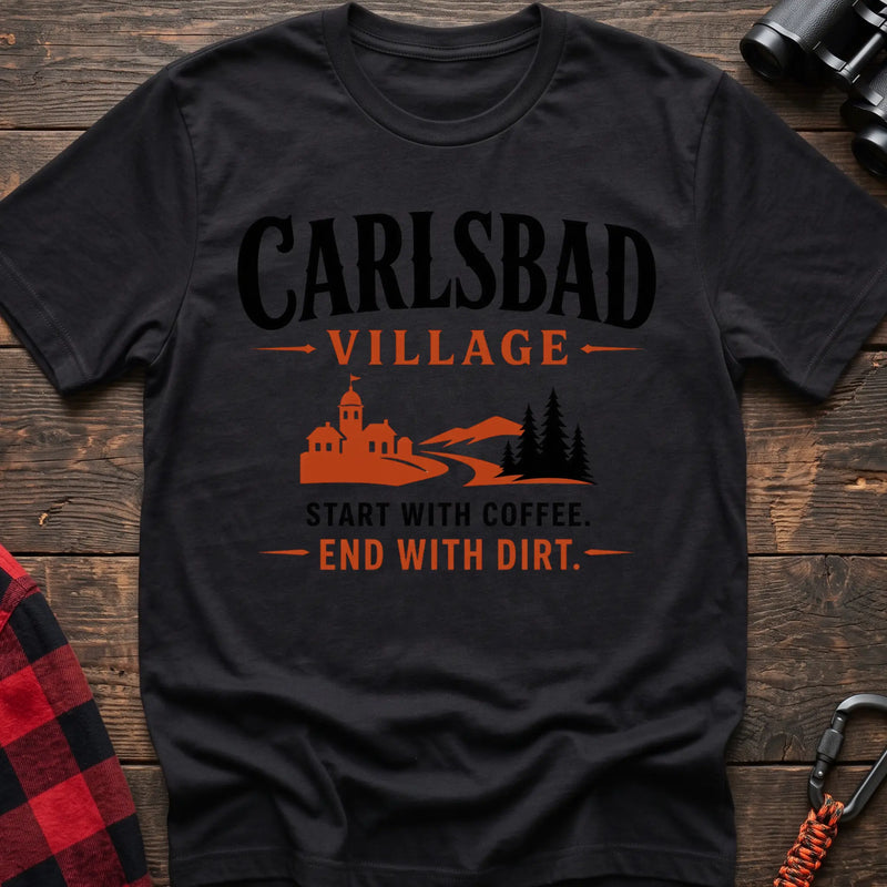 Black cotton t-shirt with a village and trail graphic and Carlsbad Village Start with Coffee End with Dirt text on rustic wood