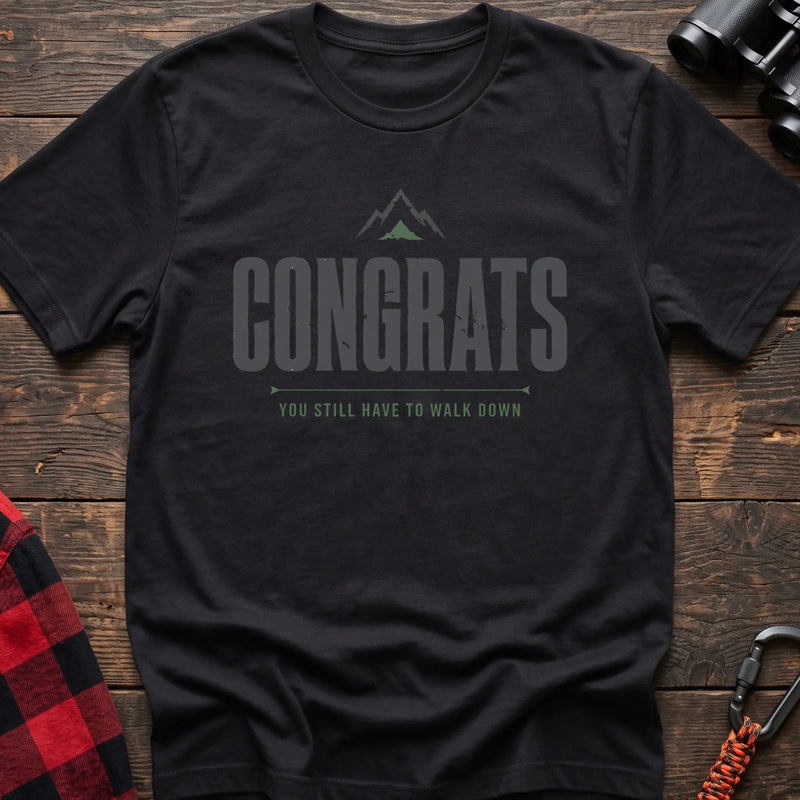Black cotton t-shirt with a mountain graphic and Congrats You Still Have to Walk Down text on rustic wood
