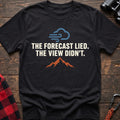 Black cotton t-shirt with a wind cloud and mountain graphic and The Forecast Lied The View Didn’t text on rustic wood