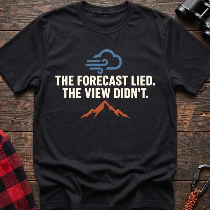 Black cotton t-shirt with a wind cloud and mountain graphic and The Forecast Lied The View Didn’t text on rustic wood