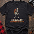Black cotton t-shirt with a hiking skeleton graphic and Hiking Is Just Walking Where You Might Die text on rustic wood