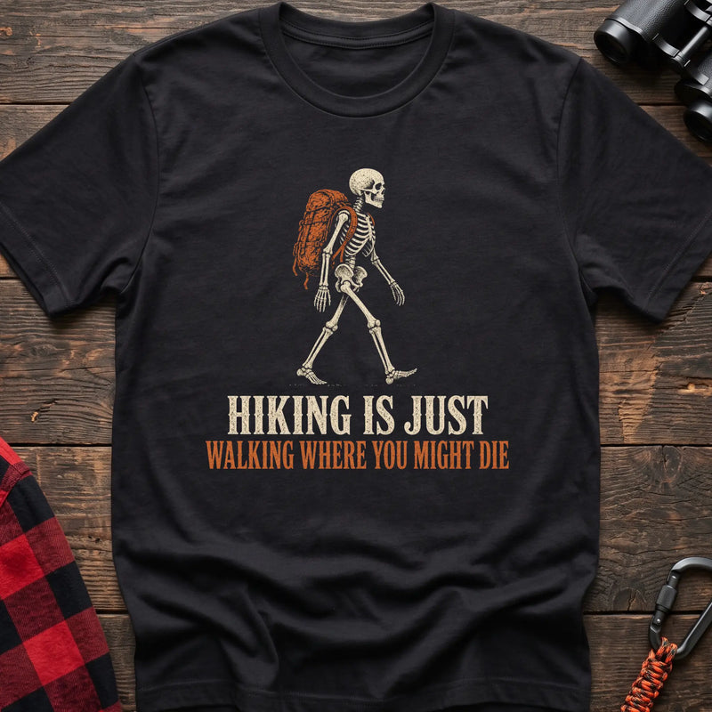 Black cotton t-shirt with a hiking skeleton graphic and Hiking Is Just Walking Where You Might Die text on rustic wood