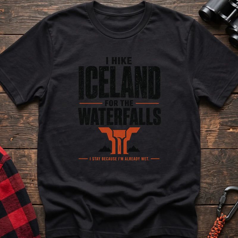 Black cotton t-shirt with a waterfall graphic and I Hike Iceland for the Waterfalls text on rustic wood