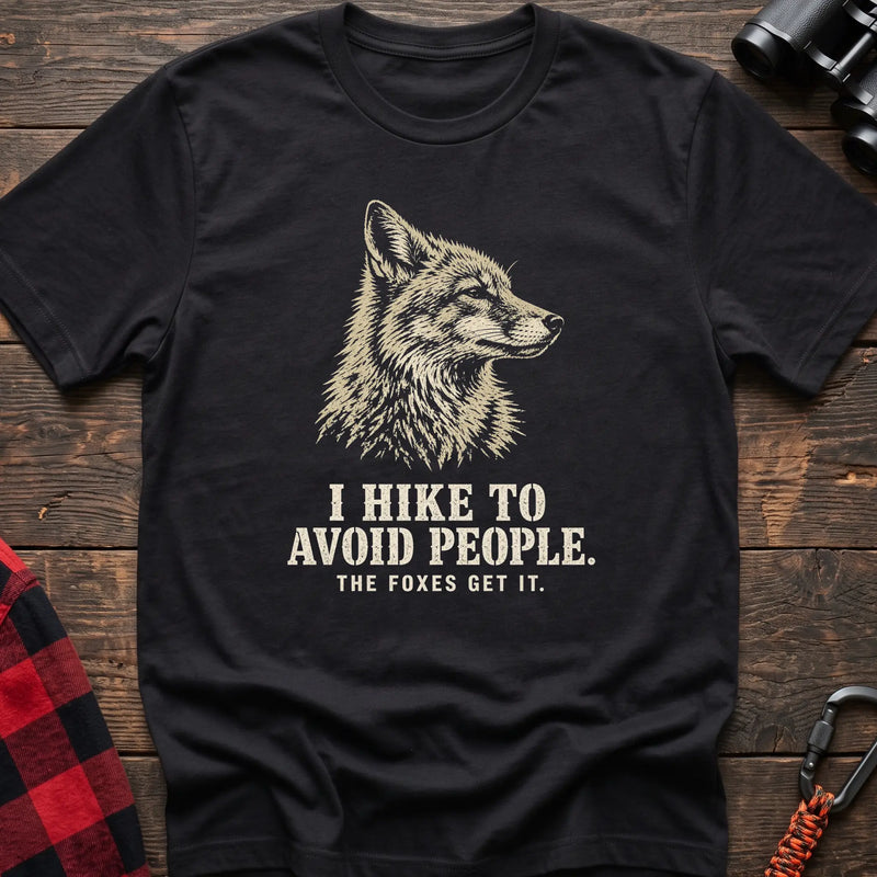 Black cotton t-shirt with a fox graphic and I Hike to Avoid People The Foxes Get It text on rustic wood