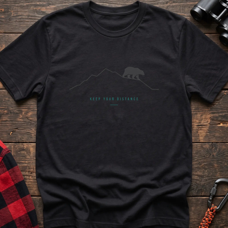 Black hiking t-shirt with a line-art mountain, walking bear, and the text “Keep Your Distance”