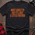 Black cotton t-shirt with Most Likely to Say It’s Just a Little Further text on rustic wood