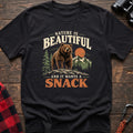 Black cotton t-shirt with a bear on a rock graphic and Nature Is Beautiful and It Wants a Snack text on rustic wood