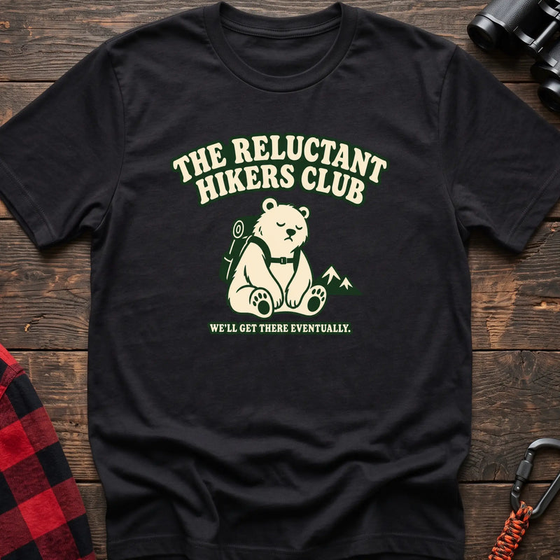 Black cotton t-shirt with a sitting backpack bear graphic and The Reluctant Hikers Club text on rustic wood