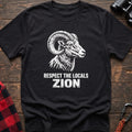 Black cotton t-shirt with a bighorn ram graphic and Respect the Locals Zion text on rustic wood