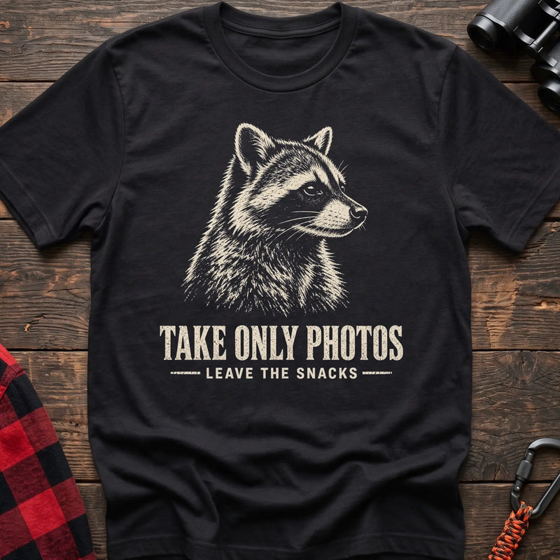 Black cotton t-shirt with a raccoon graphic and Take Only Photos Leave the Snacks text on rustic wood