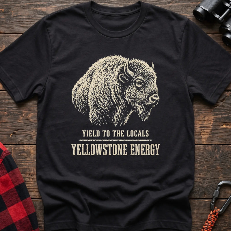 Black cotton t-shirt with a bison graphic and Yield to the Locals Yellowstone Energy text on rustic wood