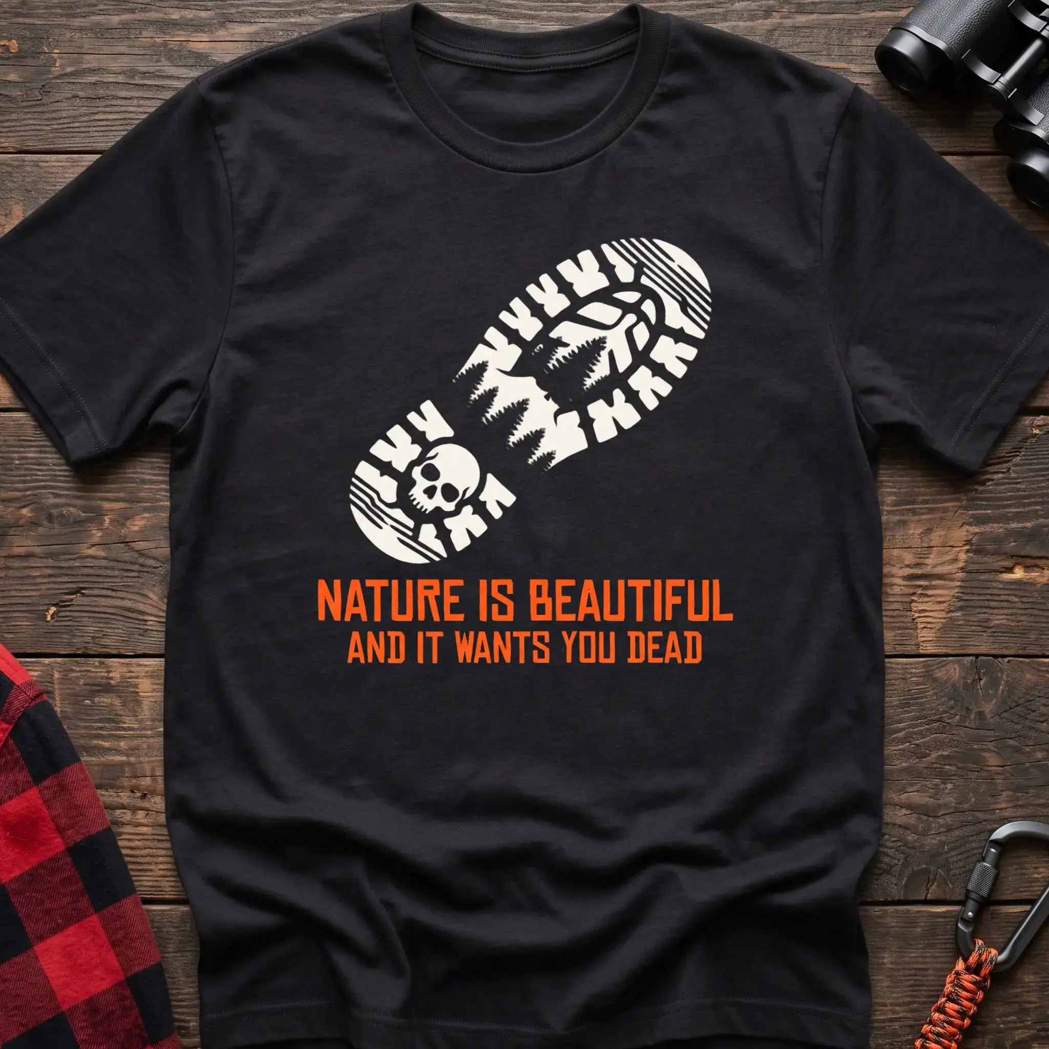 Black t-shirt with white boot print graphic featuring a skull and pine trees, and orange text reading Nature Is Beautiful And It Wants You Dead