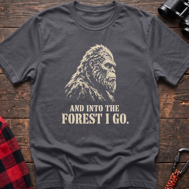 Charcoal cotton t-shirt with a Bigfoot graphic and And Into the Forest I Go text on rustic wood