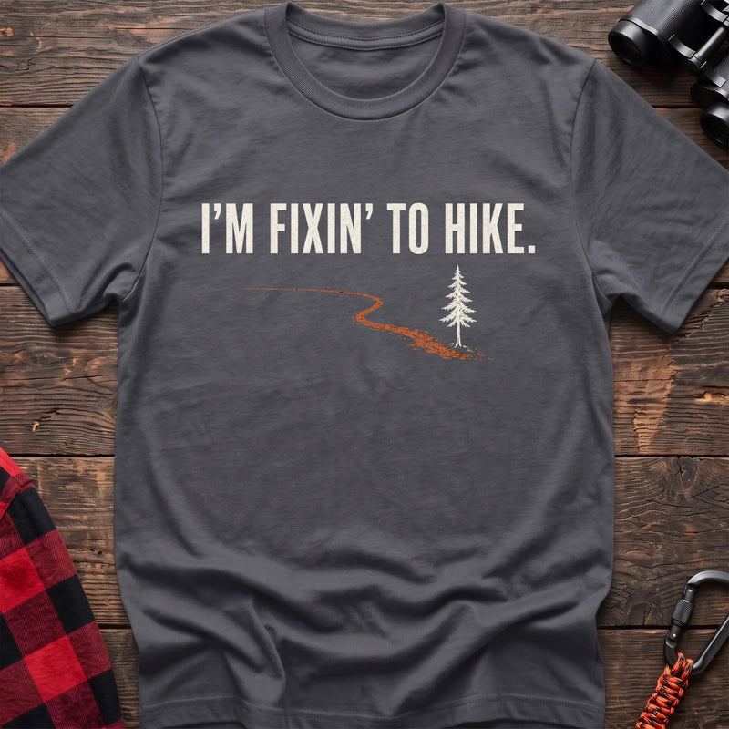 Charcoal cotton t-shirt with a trail and pine graphic and I’m Fixin’ to Hike text on rustic wood
