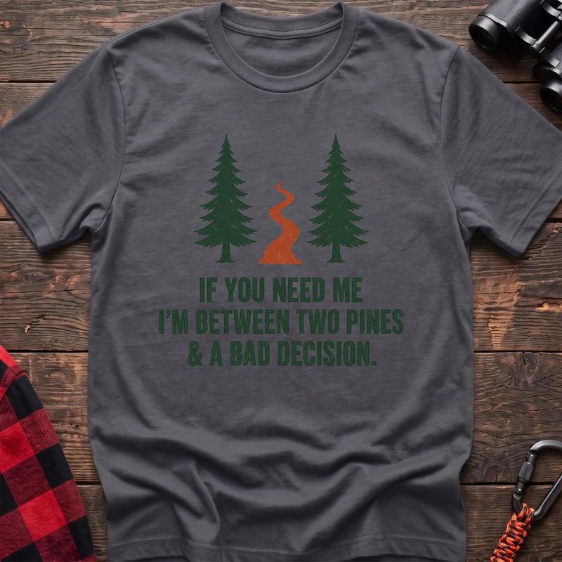Charcoal cotton t-shirt with two pines and a trail graphic and If You Need Me I’m Between Two Pines and a Bad Decision text on rustic wood