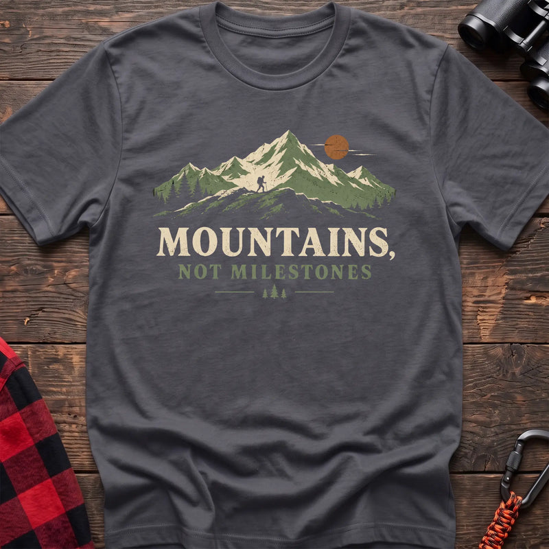 Charcoal cotton t-shirt with a hiker and mountain graphic and Mountains Not Milestones text on rustic wood