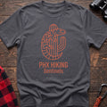 Charcoal t-shirt with orange line-art Gila monster wrapped around a saguaro cactus and the text “PHX HIKING Sentinels”