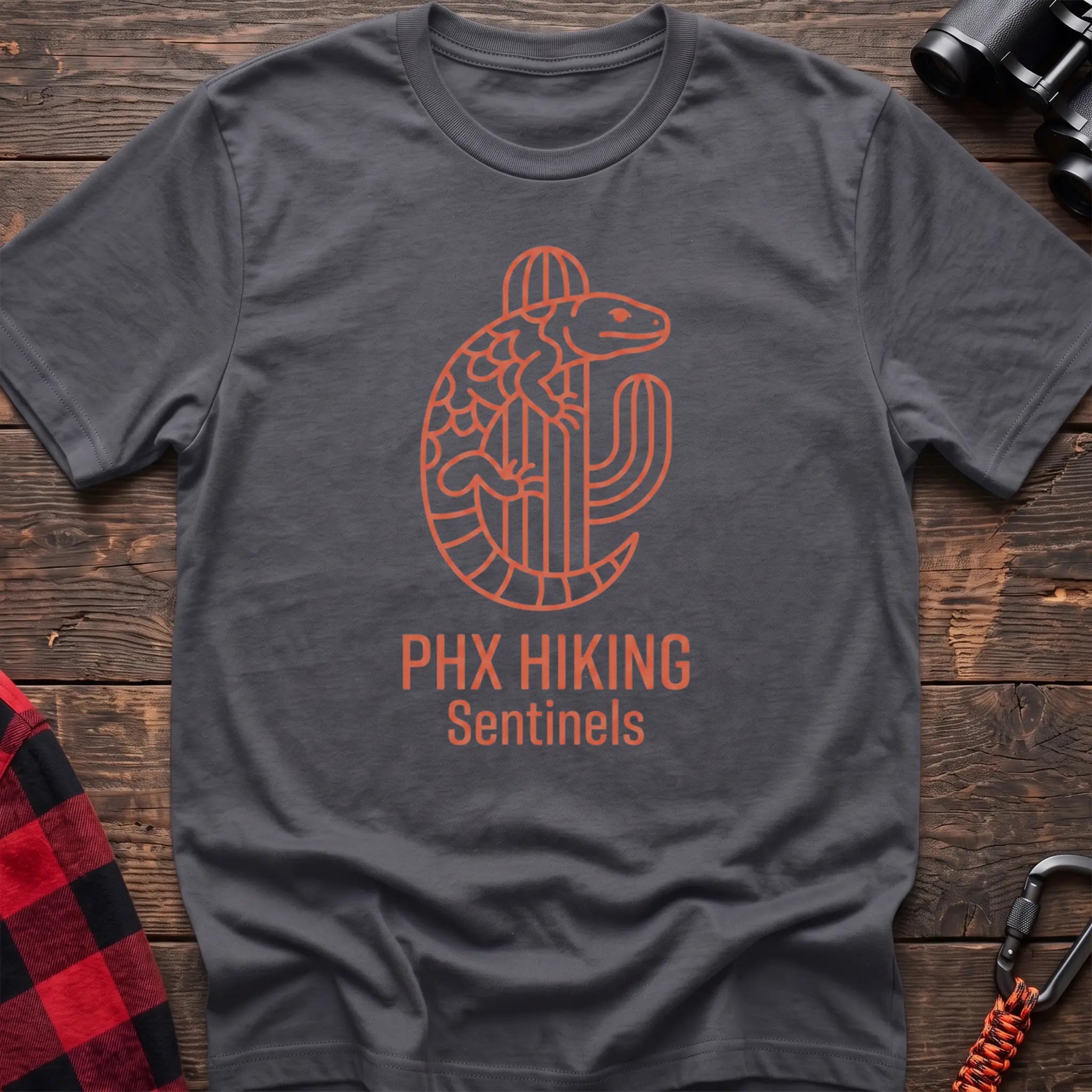 Charcoal t-shirt with orange line-art Gila monster wrapped around a saguaro cactus and the text “PHX HIKING Sentinels”