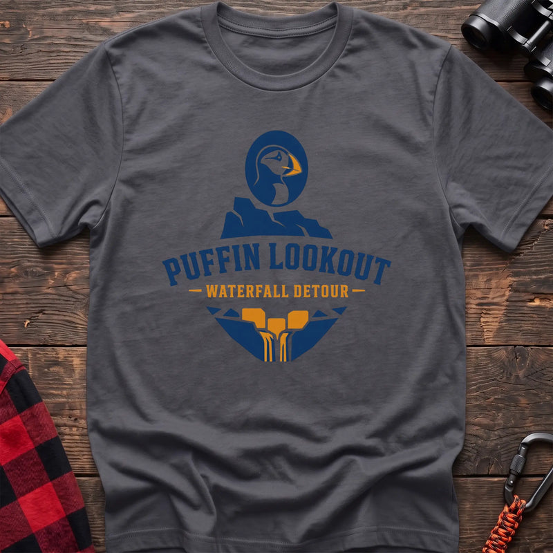 Charcoal cotton t-shirt with a puffin and waterfall graphic and Puffin Lookout Waterfall Detour text on rustic wood