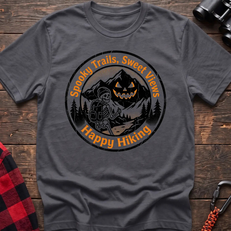 Charcoal t-shirt with circular graphic of a skeleton hiker giving a thumbs up in front of a jack-o-lantern mountain, reading Spooky Trails Sweet Views Happy Hiking