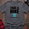 Charcoal cotton t-shirt with a waterfall graphic and Take a Hike Preferably Under a Waterfall Iceland text on rustic wood