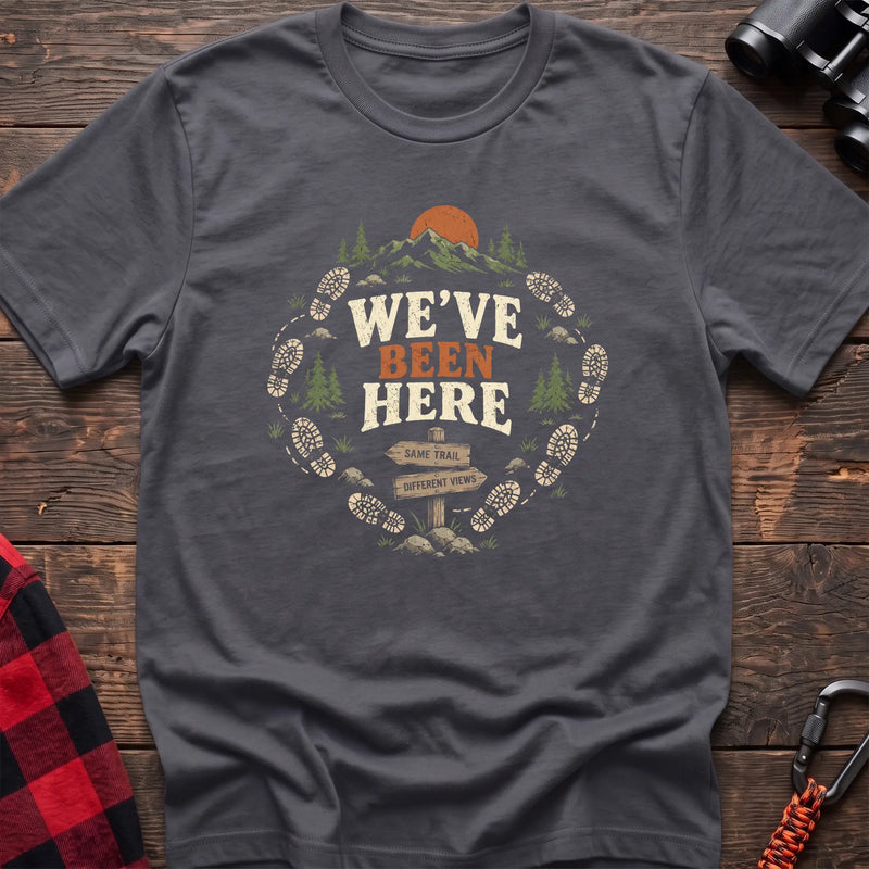 Charcoal cotton t-shirt with a bootprint circle and trail sign graphic and We’ve Been Here text on rustic wood