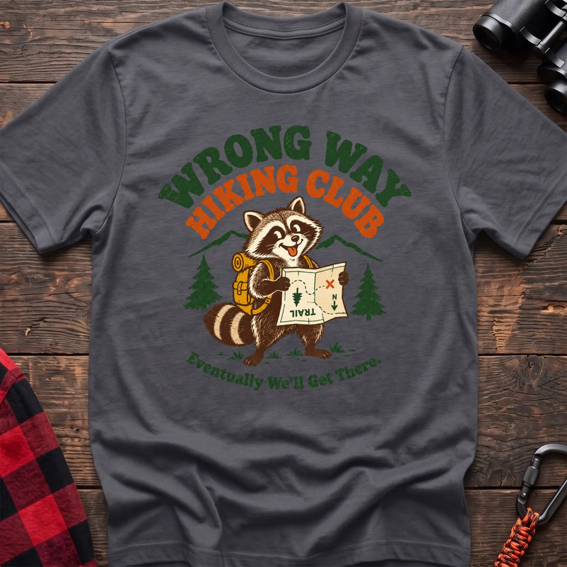 Charcoal cotton t-shirt with a raccoon holding a map graphic and Wrong Way Hiking Club text on rustic wood