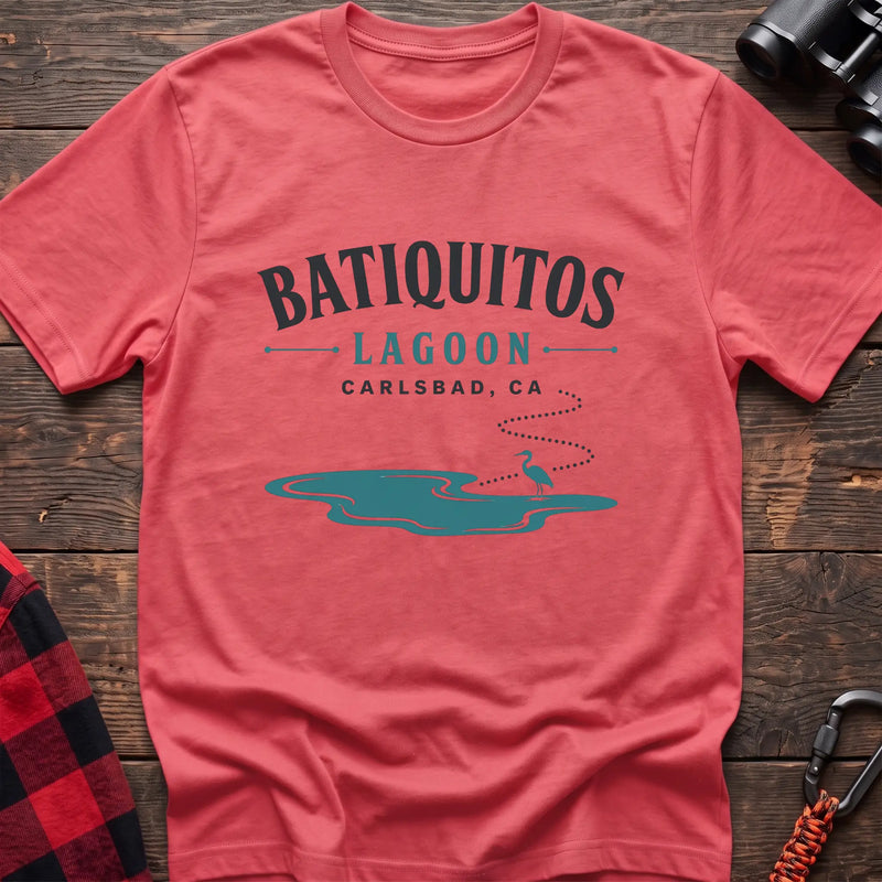 Coral silk cotton t-shirt with a heron and lagoon graphic and Batiquitos Lagoon Carlsbad CA text on rustic wood