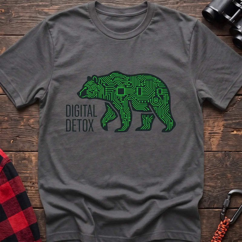 Graphite heather t-shirt with a neon green circuit-board patterned silhouette of a walking bear, and the text “DIGITAL DETOX” printed to the left of the design, laid flat on a wooden surface.
