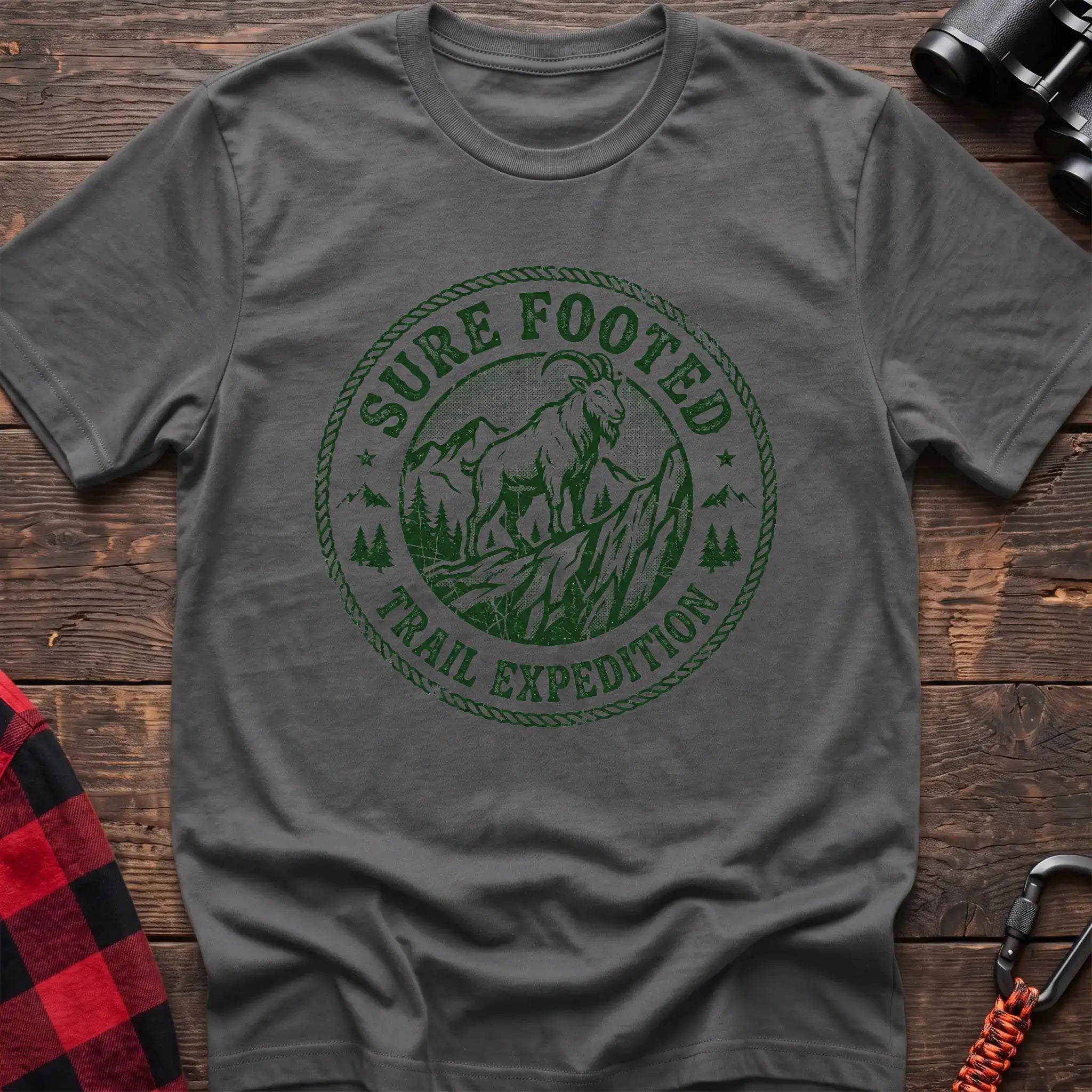 Graphite heather t-shirt with circular badge graphic of a mountain goat on a rocky peak reading Sure Footed Trail Expedition