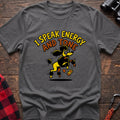 Graphite heather t-shirt with a cartoon yellow and black poodle jumping excitedly next to a falling energy drink can, with the arched text “I SPEAK ENERGY AND TONE,” laid flat on a wooden surface.