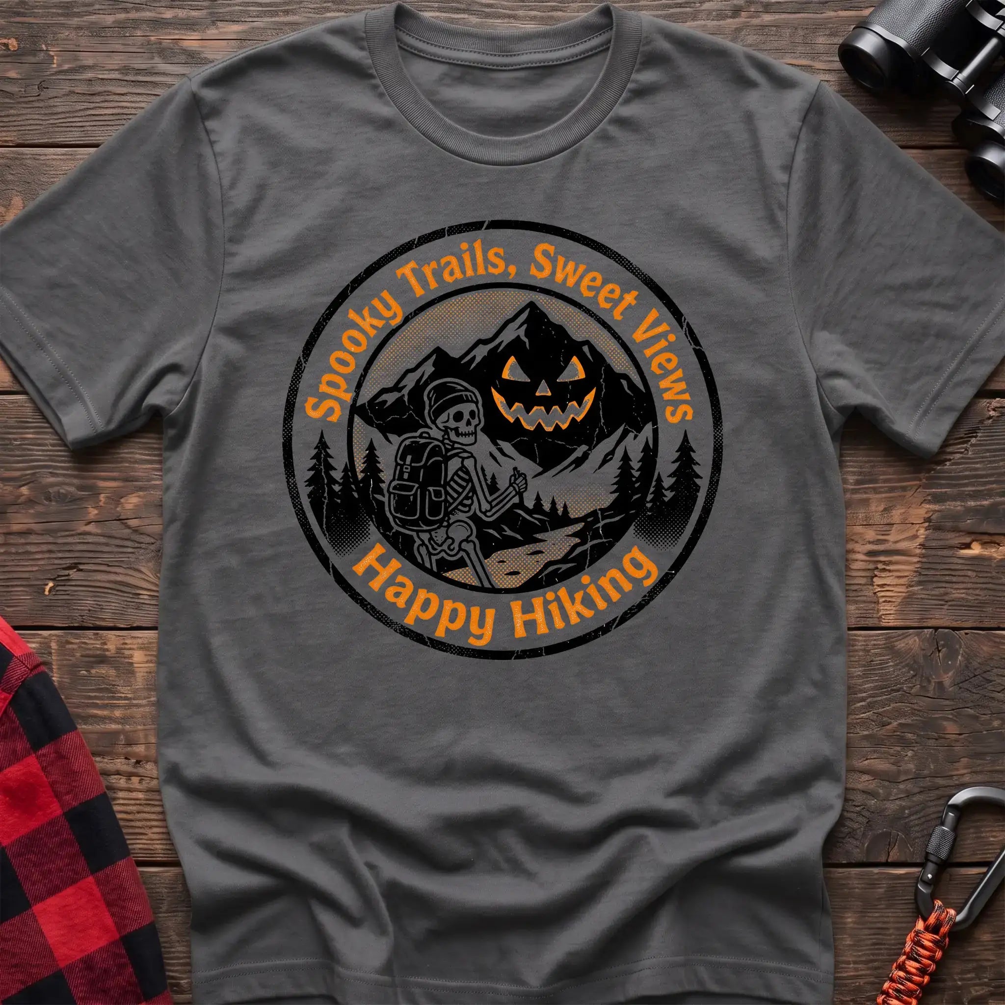 Graphite heather t-shirt with circular graphic of a skeleton hiker giving a thumbs up in front of a jack-o-lantern mountain, reading Spooky Trails Sweet Views Happy Hiking