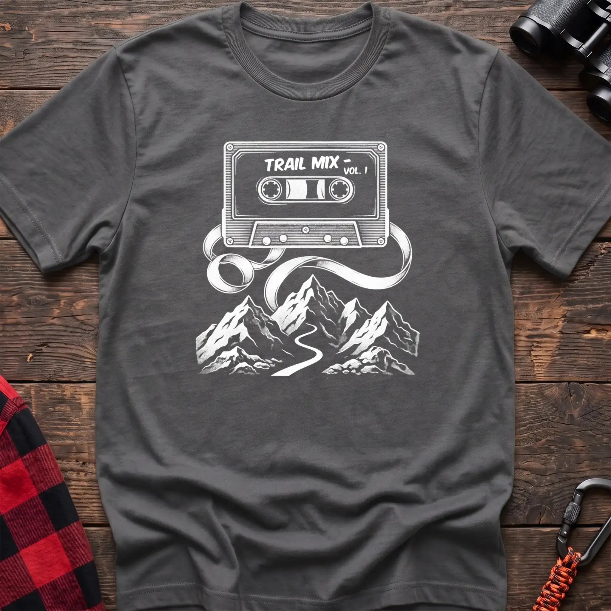 Graphite heather t-shirt with white cassette tape graphic labeled Trail Mix Vol. 1, with tape unspooling into a trail through mountains