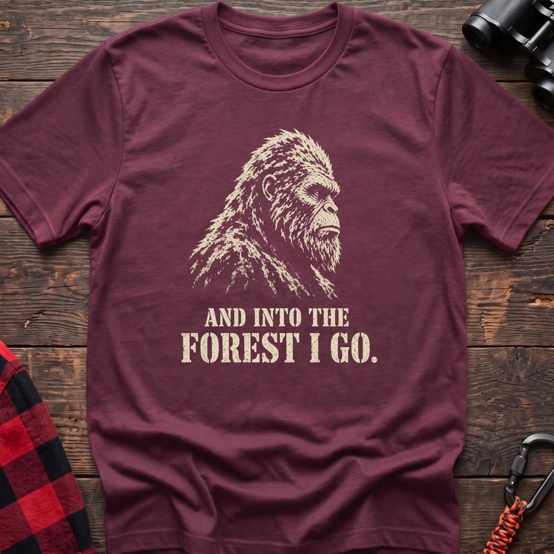 Heather maroon cotton t-shirt with a Bigfoot graphic and And Into the Forest I Go text on rustic wood