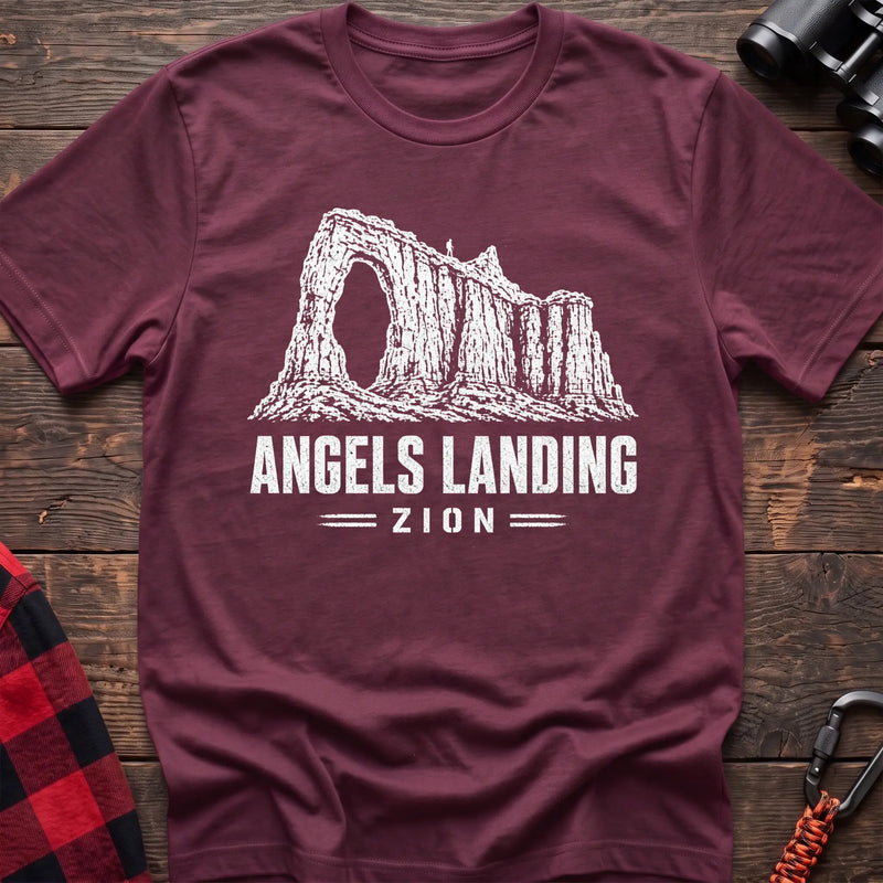 Heather maroon cotton t-shirt with a canyon graphic and Angels Landing Zion text on rustic wood
