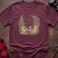 Heather maroon cotton t-shirt with a mushroom and fern graphic and Forage the Quiet text on rustic wood