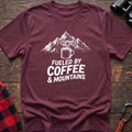 Maroon t-shirt with white graphic of a steaming coffee mug in front of mountains and the text Fueled by Coffee & Mountains