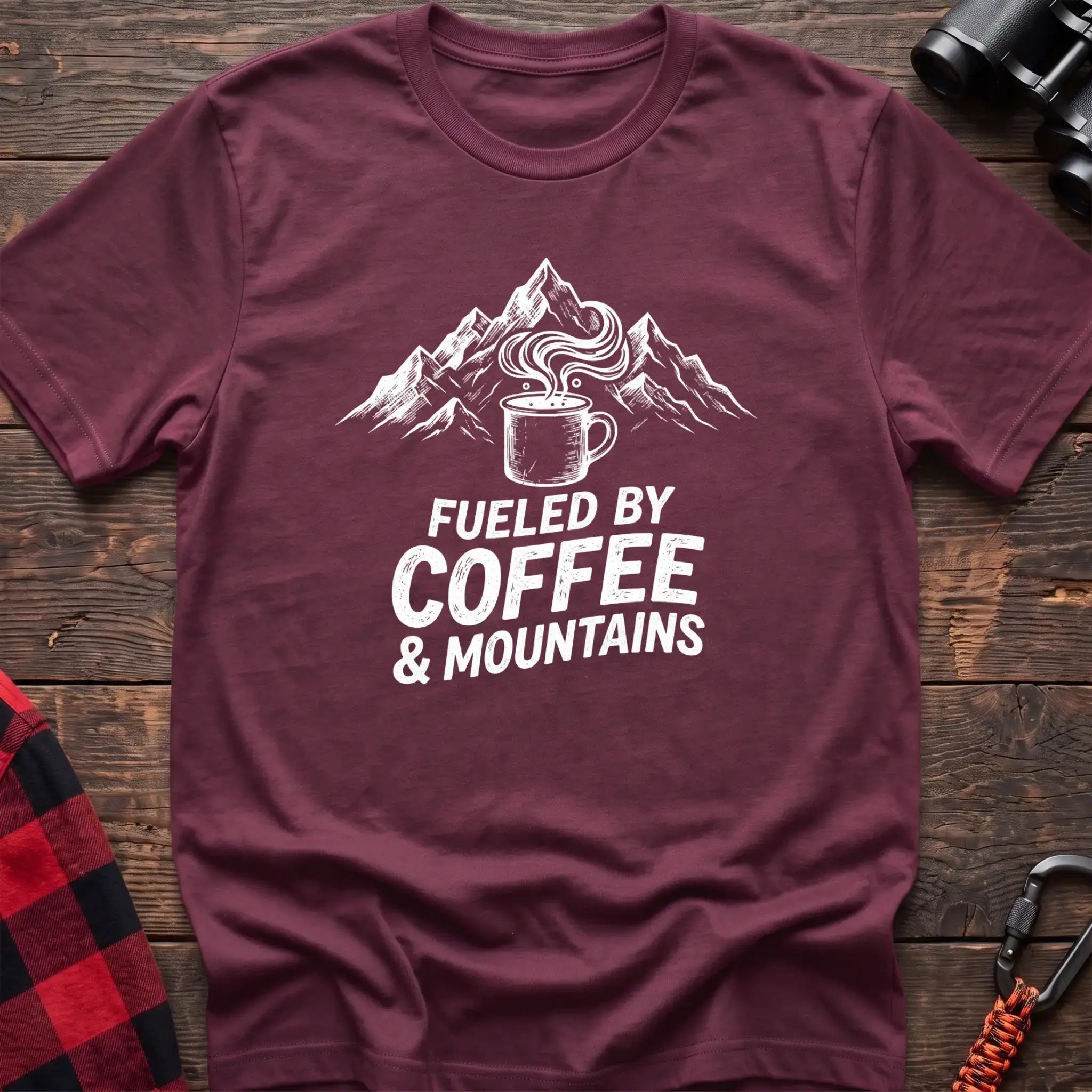 Maroon t-shirt with white graphic of a steaming coffee mug in front of mountains and the text Fueled by Coffee & Mountains