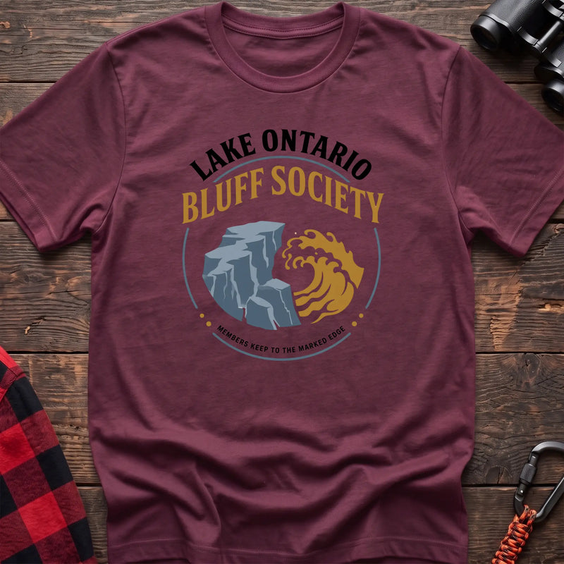 Heather maroon hiking t-shirt with Lake Ontario Bluff Society badge showing a cliff, wave, and Members Keep to the Marked Edge