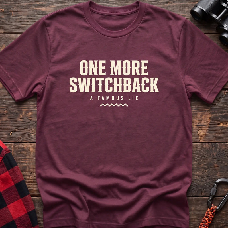 Heather maroon cotton t-shirt with One More Switchback A Famous Lie text on rustic wood