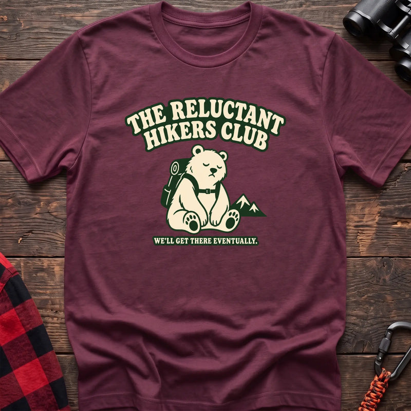 Heather maroon cotton t-shirt with a sitting backpack bear graphic and The Reluctant Hikers Club text on rustic wood