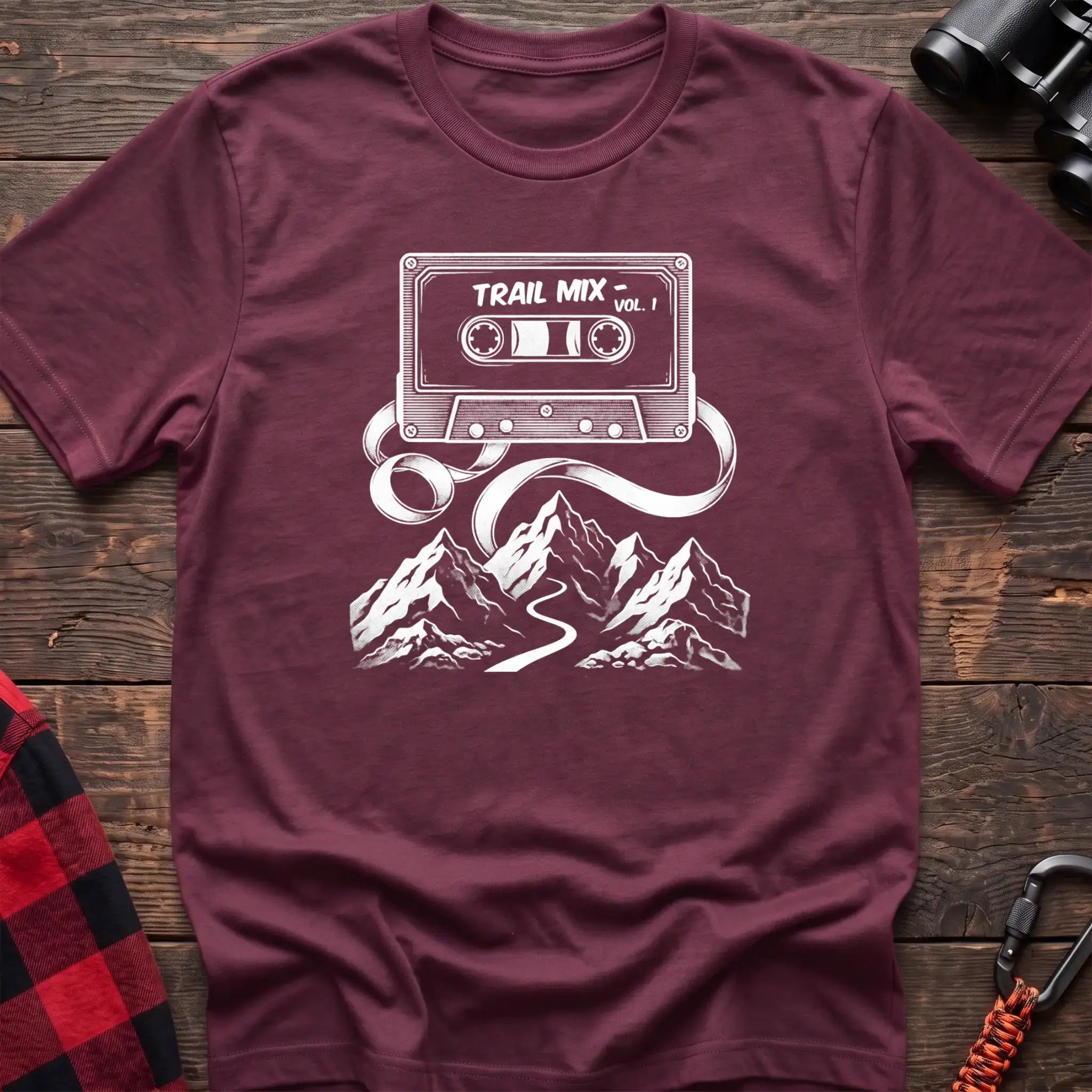 Heather maroon t-shirt with white cassette tape graphic labeled Trail Mix Vol. 1, with tape unspooling into a trail through mountains