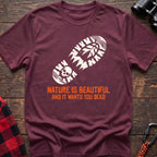 Heather maroon t-shirt with white boot print graphic featuring a skull and pine trees, and orange text reading Nature Is Beautiful And It Wants You Dead