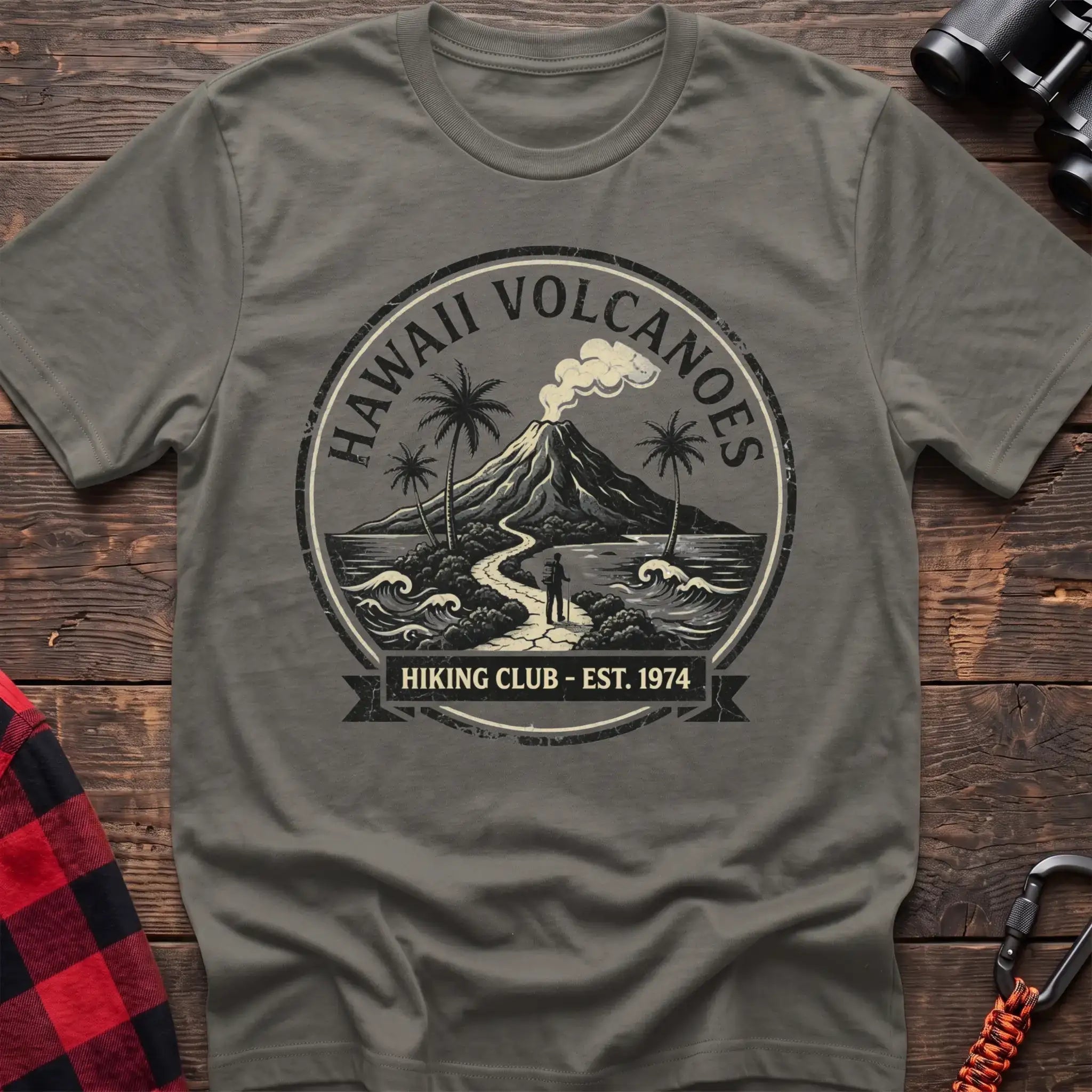Heather military green t-shirt with circular Hawaii Volcanoes badge graphic showing a volcano, palm trees, and a hiker, reading Hiking Club Est 1974