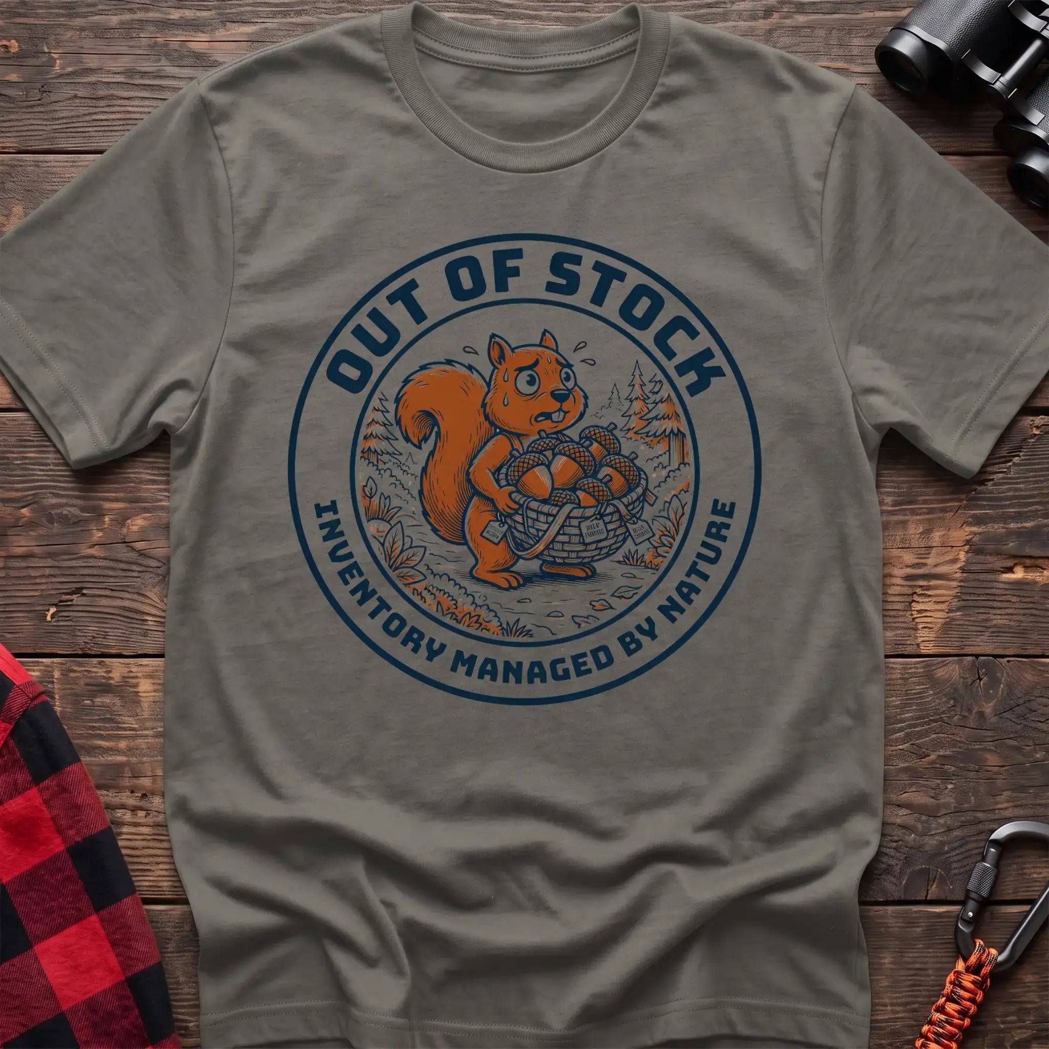Heather military green t-shirt with circular graphic of a stressed squirrel holding a basket of acorns, reading Out of Stock Inventory Managed by Nature