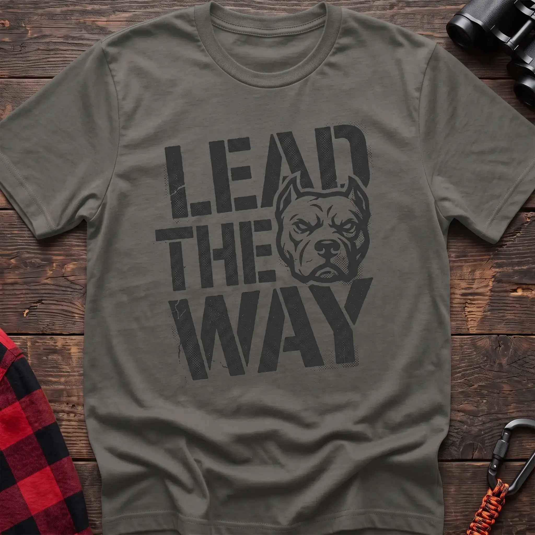 Heather military green t-shirt with a distressed graphic of a stern pit bull head integrated into the bold text “LEAD THE WAY,” laid flat on a wooden surface.