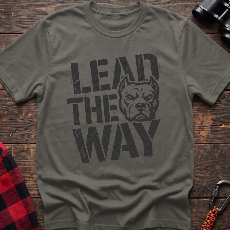 Heather military green t-shirt with a distressed graphic of a stern pit bull head integrated into the bold text “LEAD THE WAY,” laid flat on a wooden surface.