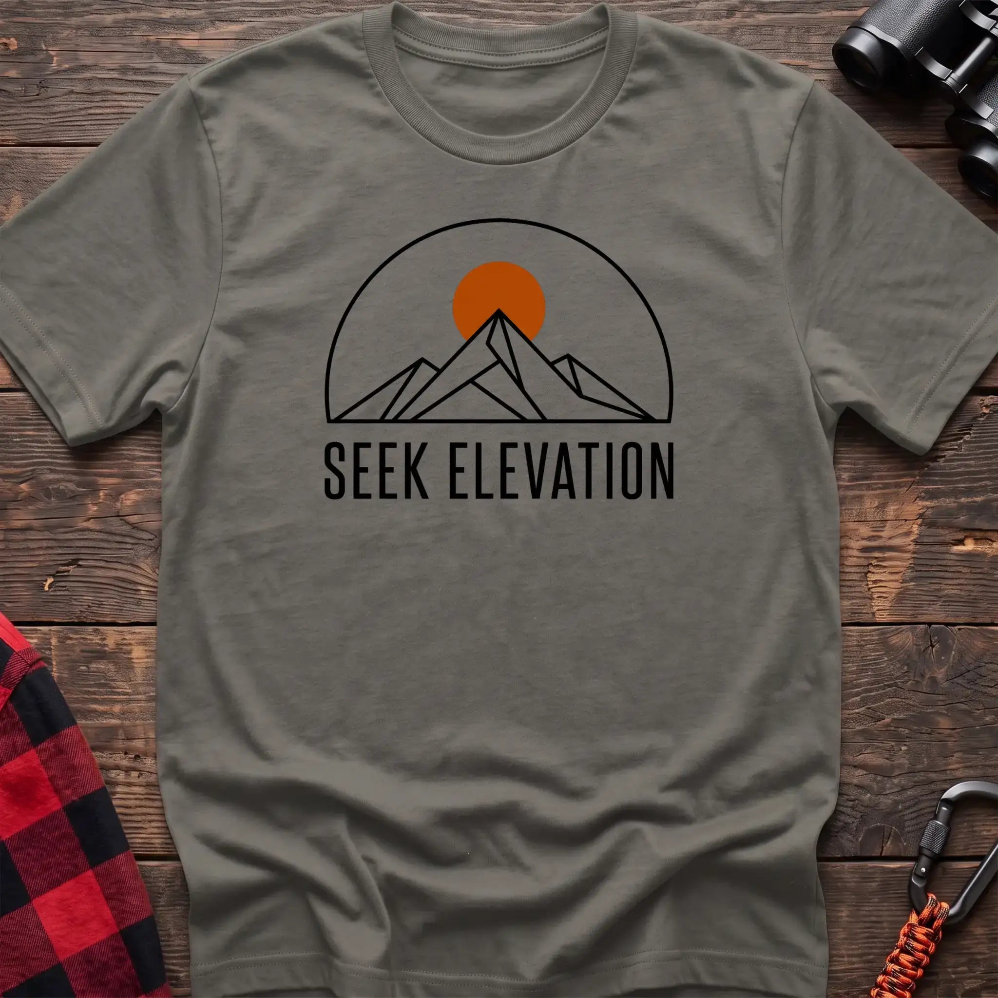 Heather military green t-shirt with minimalist mountain and sun graphic reading Seek Elevation