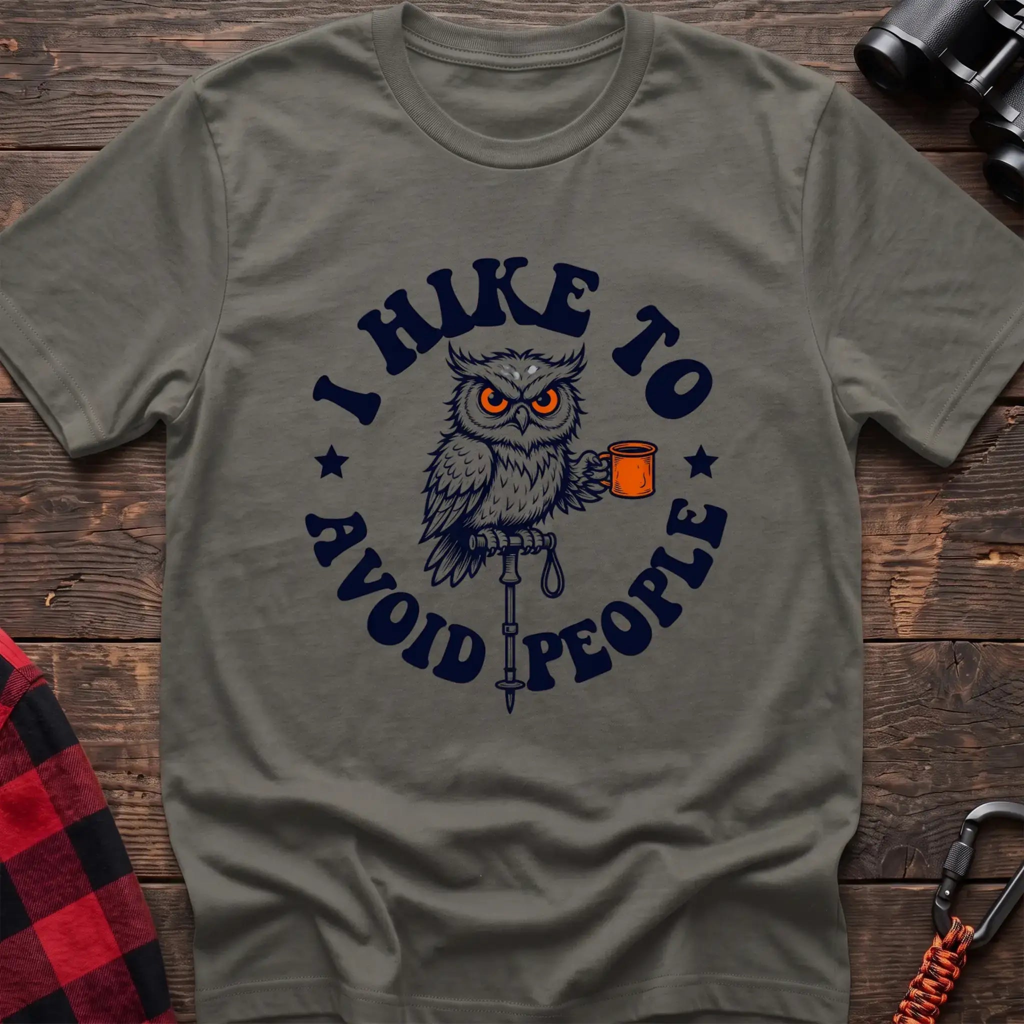 Heather military green t-shirt with owl holding a camping mug on a hiking pole and the text I Hike to Avoid People